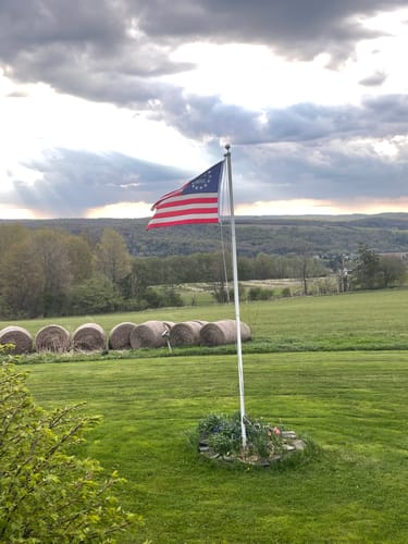 Customer's beautiful Betsy Ross Flag flying on a flagpole in a scenic rural landscape.