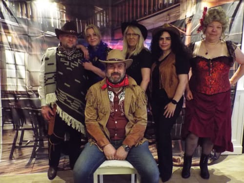 Customer and friends in fun cowboy costumes playing the Wild West Cowboy Murder Mystery game.