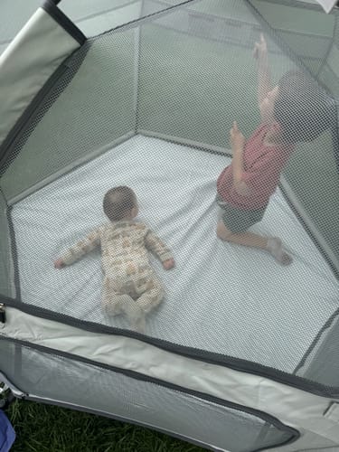 Customer's grey Pop 'N Go Playpen with two children playing inside on the grass.