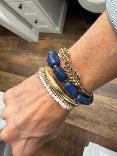 Customer wearing the blue Rectangular Clay Bead Bracelet stacked with other gold and white bracelets.