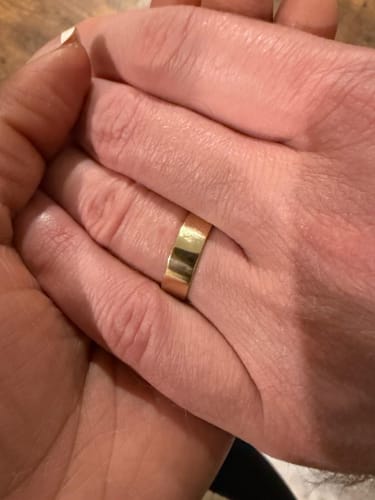 Close-up of a customer wearing the high-polish gold Flat Band while holding another person's hand.