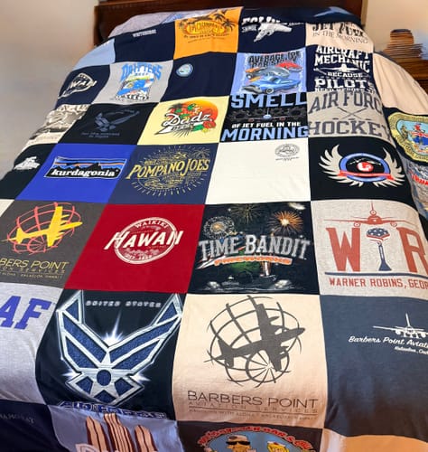 Customer's custom T-Shirt Quilt on a bed, showing colorful squares from various Air Force and travel t-shirts.
