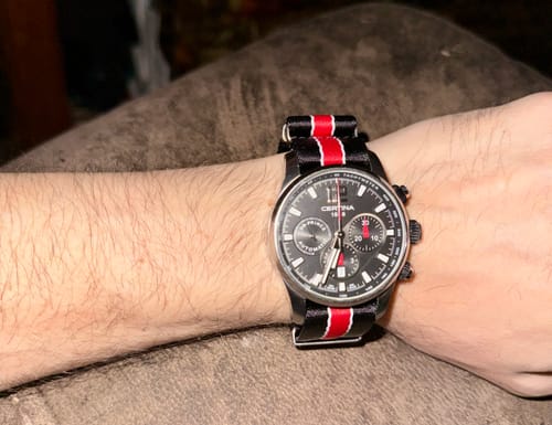Customer wearing the AlphaPremier Racing Stripe watch strap on a black chronograph watch, showing the full wrist.