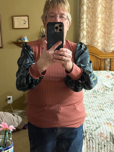 Customer wearing the Meadowlane Blouse, showing the ribbed pink bodice and contrasting patterned sleeves.