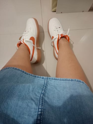 Customer wearing the white Nike Court Vision Low shoes with orange accents and gum soles.