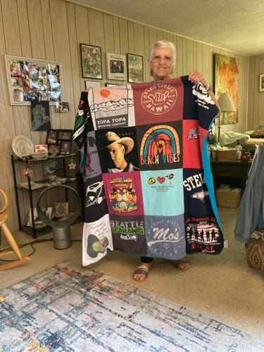 Reviewer holding up their colorful Project Repat T-Shirt Quilt, showing various custom shirt squares.