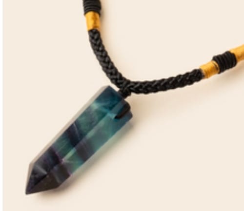 Customer's fluorite crystal necklace with a pointed, multicolored stone on a braided black cord.
