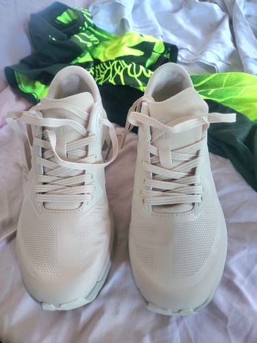 Customer's off-white On Cloudzone Women's Casual Shoes viewed from the front, resting on a bed.