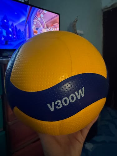 Customer holding the textured yellow and blue Mikasa MIK-V300W Volleyball in one hand.