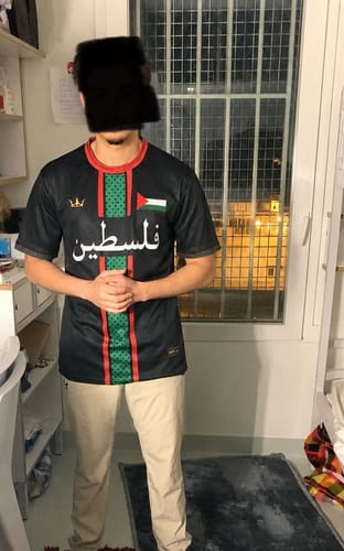 Customer wearing the front of the black Palestine Heritage Custom Football Jersey with Arabic text.