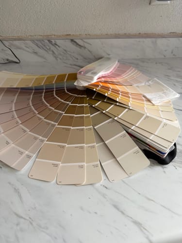 Customer's Dunn-Edwards Perfect Palette Color Fan Deck fanned out on a marble countertop, showing a wide range of color swatches.