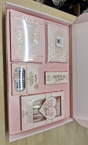 Customer's open pink P. Louise Budget Box showing a makeup palette, lashes, a lip kit, and other items neatly arranged inside.
