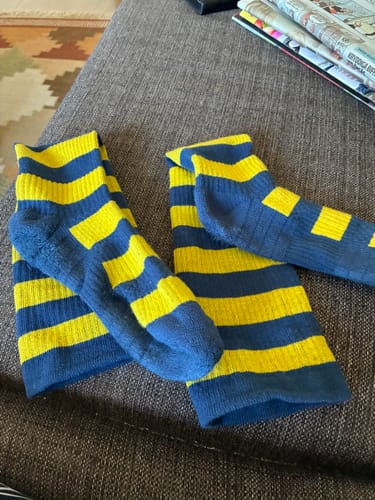 Kundens blå- och gulrandiga Diasocks stödstrumpor som ligger på en soffa.
