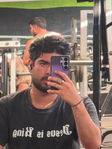 Cliente en un gimnasio mostrando la funda Illuminati Python Iris Bloom en una selfie de espejo.