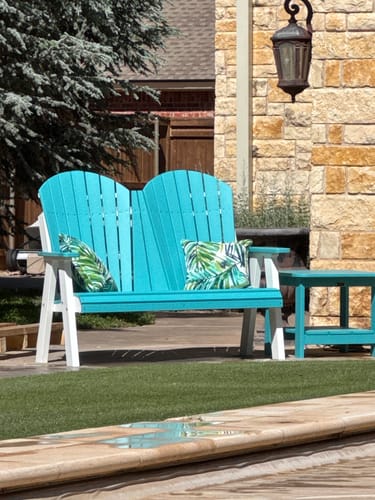 Customer's bright turquoise and white Adirondack Park Bench sitting on a lawn next to a patio.