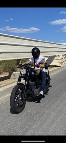 Client portant le T-shirt Pirate Ride Fast Live Free sur une moto sur une route ensoleillée.