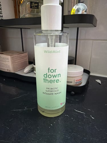 Customer's Probiotic Intimate Wash pump bottle on a black counter among other bathroom products.