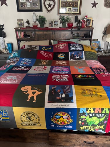 Customer's colorful Project Repat T-Shirt Quilt, made from many different t-shirts, displayed on a bed.