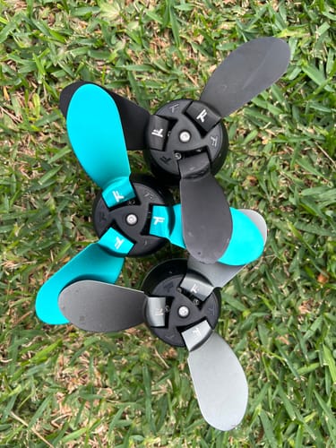 Reviewer's three Foildrive Low Range Propellers on grass, showing the different black, grey, and blue blades.