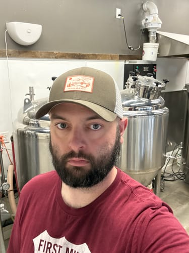 Reviewer wearing the olive green Big Trucker Hat with a white mesh back.