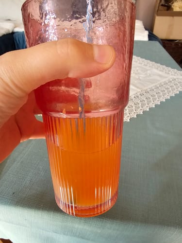Rezensent hält ein Glas mit Saft, frisch gepresst aus den Früchten der Bio Obstbox „Kreta-Liebe“.