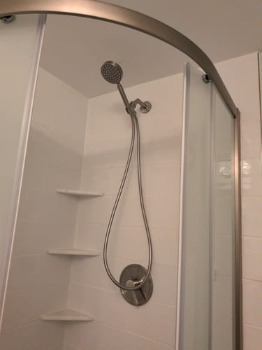 Reviewer's installed 1-Handle Shower System with a handheld spray in a white tiled shower stall.