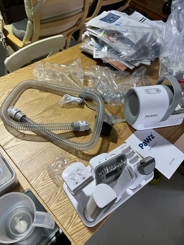 Reviewer's GroomMate Pet Grooming Kit unboxed, showing the vacuum, hose, and attachments in a tray on a table.