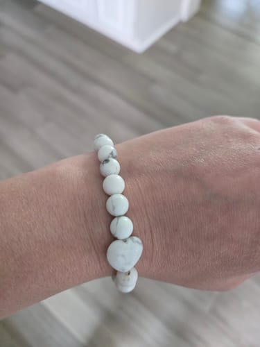 Reviewer's white crystal bracelet with a heart-shaped bead on their wrist.