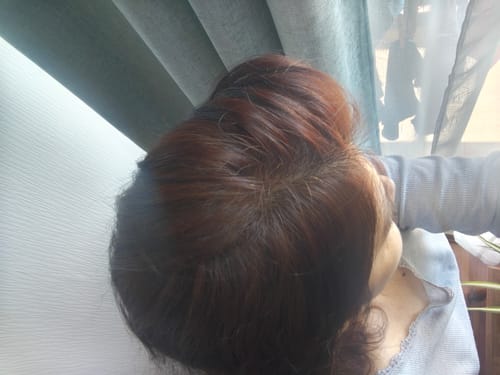 Clienta mostrando el resultado final del Tinte 100% Natural en su cabello recogido, con un tono castaño uniforme.