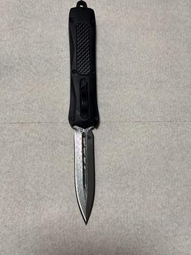 Reviewer's Black Zedd D/A OTF knife with its double-edged Damascus steel blade extended.