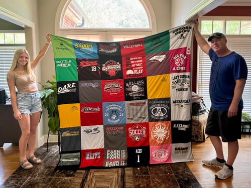 Customer and a young person holding up a large, colorful Premium T Shirt Quilt made from many t-shirts.