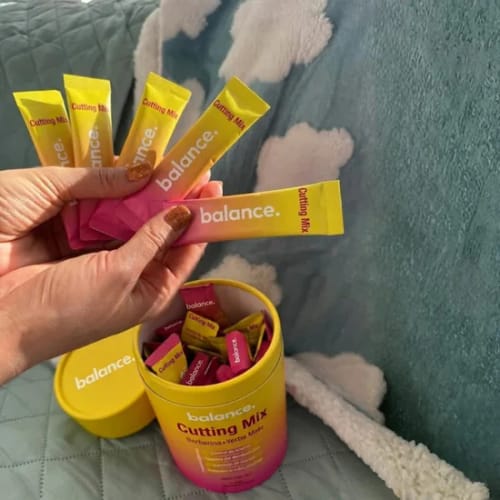Una clienta sostiene los sobres amarillos de Lumi Balance Drink™ sobre el envase abierto.