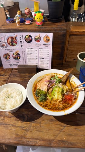 A customer's photo of a bowl of ramen and a side of rice on a wooden table; the product is not visible.