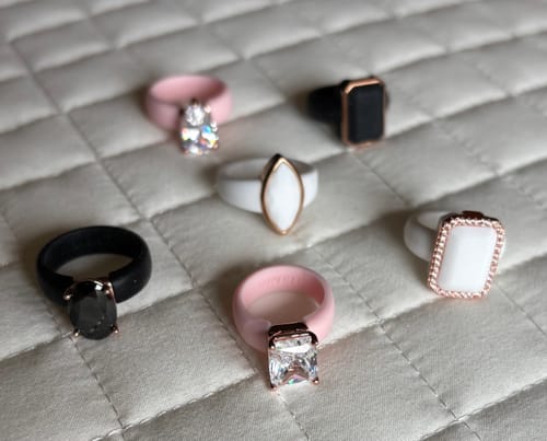 Reviewer's collection of seven silicone rings in pink, black, and white, with various stone shapes.