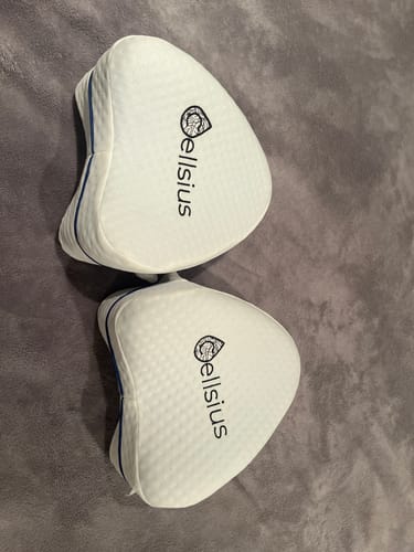 Client montrant ses deux coussins orthopédiques pour genoux Cellsius sur une couverture.