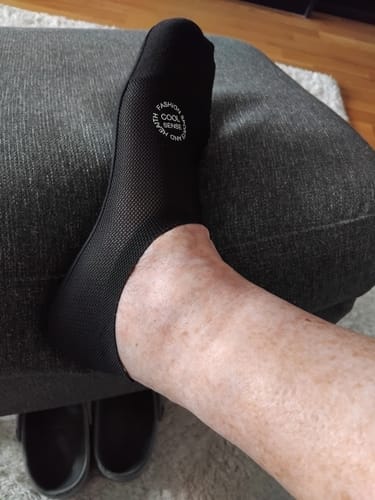 Kund som visar den svarta, bekväma ankelstrumpan med kompression på sin fot.