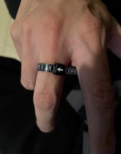Customer's hand with the black FREE RING SIZER wrapped around a finger to measure the size.