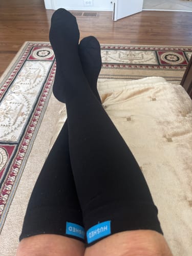 Reviewer relaxing with their legs crossed, wearing black Eucalyptus Lyocell Compression Socks.