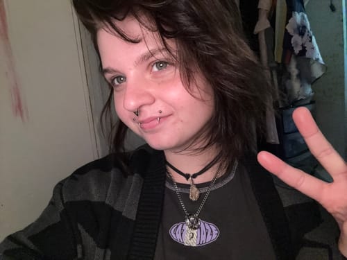 Close-up of a reviewer smiling while wearing the Cuban Chain layered with another necklace.