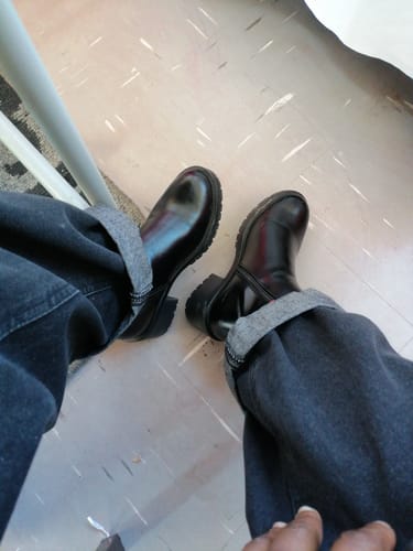 Customer's overhead view of the shiny, black Miss Black Creek 1 Ankle Boots paired with cuffed jeans.
