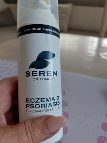 Egy vásárló kezében tartja a SERENI pikkelysömör és ekcéma krém fehér flakonját.