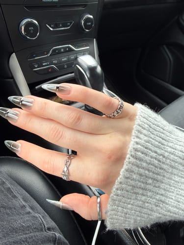 A customer's hand wearing the silver Barbed Wire Ring on their middle finger while sitting in a car.