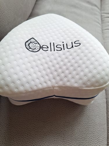 Client montrant le coussin orthopédique Cellsius blanc sur un canapé.