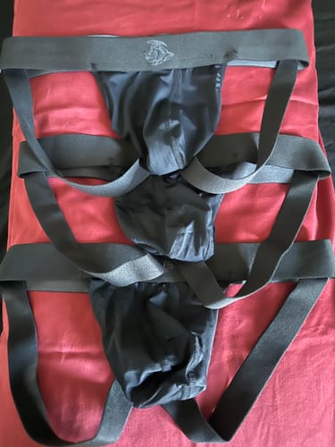 Customer's three black Nylon Mesh Jockstraps from the 3-pack laid out on a red surface.