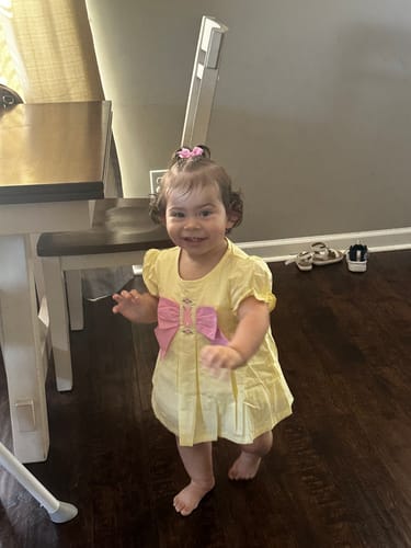 Customer's child smiling while wearing the yellow Bunny & Flowers Isabella Skirt Bubble indoors.