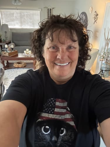 Reviewer smiling while wearing the black Statement Made USA t-shirt with a cat and American flag hat design.