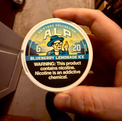 Customer holding a white can of Drifters Blueberry Lemonade Ice nicotine pouches.