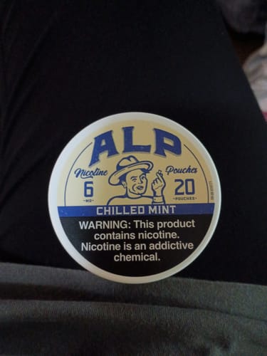 Customer's round can of ALP Chilled Mint Nicotine Pouches resting on their lap.