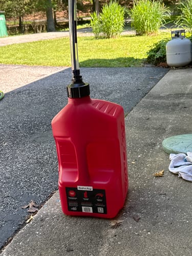 Customer's red 5 Gallon Jug with its spout attached, sitting on a concrete driveway.