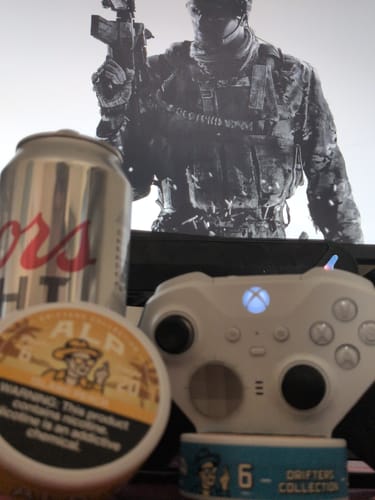 Customer's can of Drifters Island Peach Nicotine Pouches on a desk with a gaming controller and a drink in front of a monitor.